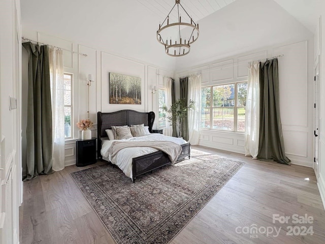 bedroom with a chandelier, vaulted ceiling, multiple windows, and light hardwood / wood-style floors