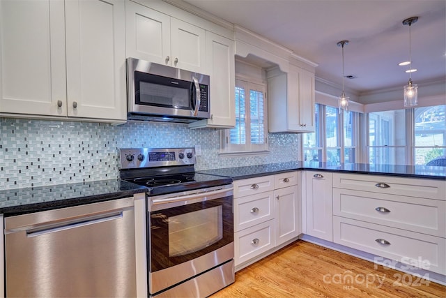 kitchen with decorative backsplash, white cabinets, light wood-type flooring, pendant lighting, and stainless steel appliances