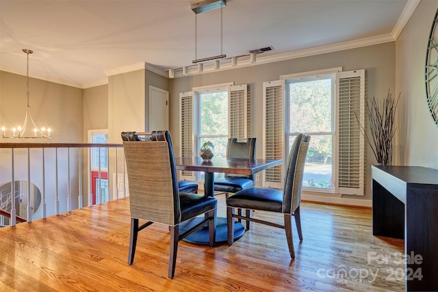 dining space featuring crown molding, a notable chandelier, and light wood-type flooring