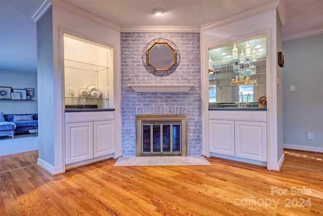 unfurnished living room with ornamental molding, sink, light wood-type flooring, and a fireplace