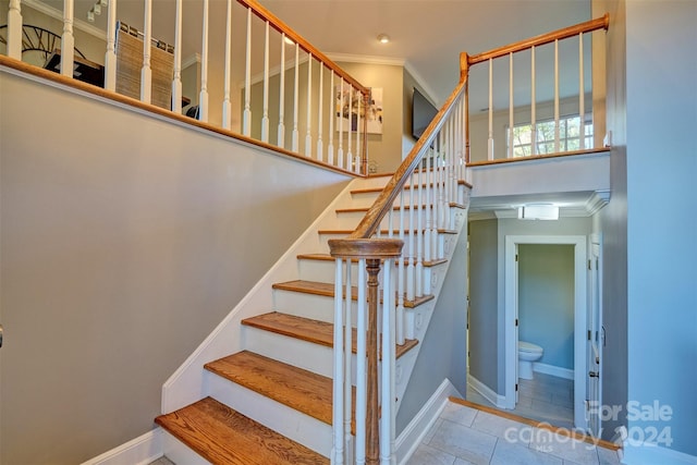 staircase with ornamental molding and tile patterned floors