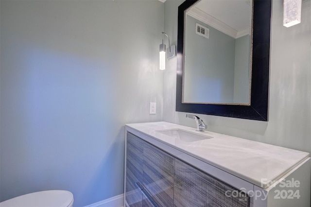 bathroom with vanity, crown molding, and toilet