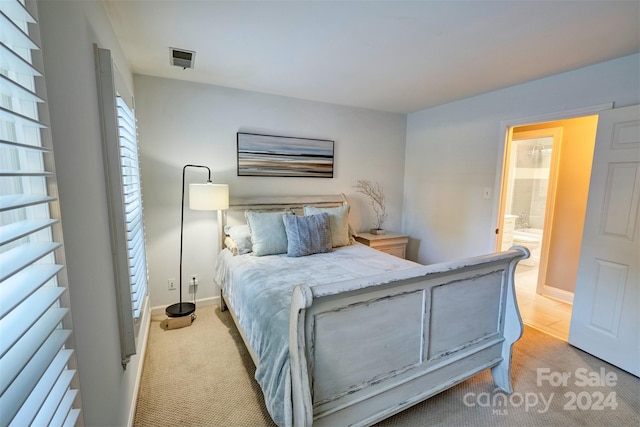 bedroom with light carpet and ensuite bath