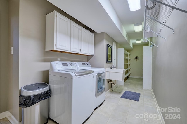 laundry room with light tile patterned flooring, cabinets, and washer and clothes dryer