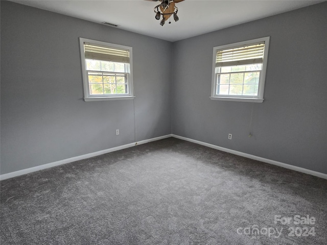 spare room with ceiling fan and dark colored carpet