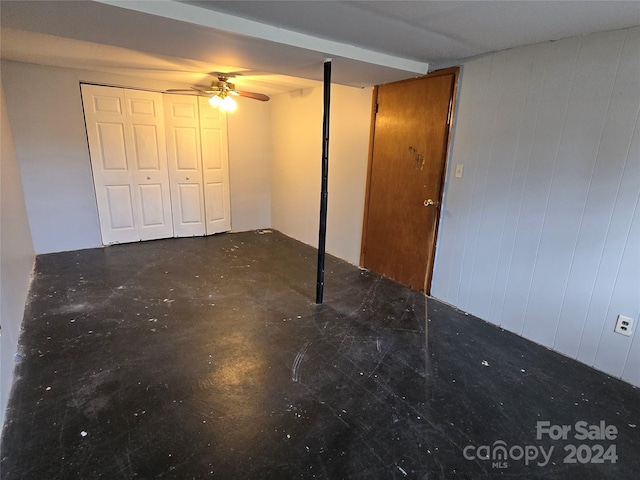 unfurnished bedroom with wood walls and ceiling fan