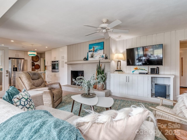 living room with a brick fireplace and ceiling fan