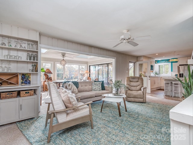 living room featuring light carpet, ceiling fan, and wood walls