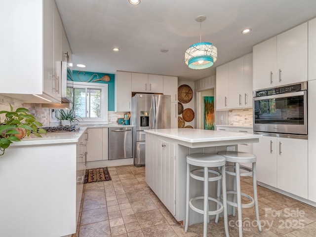 kitchen with decorative backsplash, a center island, stainless steel appliances, and white cabinetry