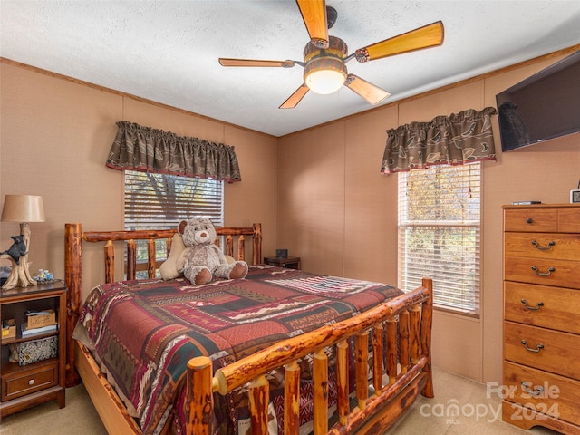 carpeted bedroom with ceiling fan, a textured ceiling, and multiple windows