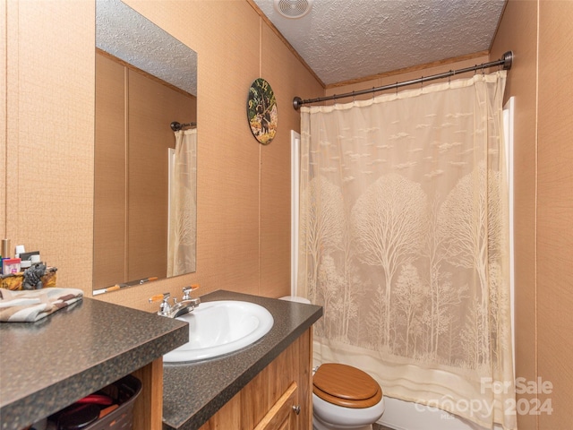 full bathroom featuring vanity, shower / bath combo with shower curtain, a textured ceiling, and toilet