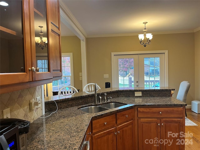 kitchen featuring a healthy amount of sunlight, sink, light hardwood / wood-style floors, and a notable chandelier