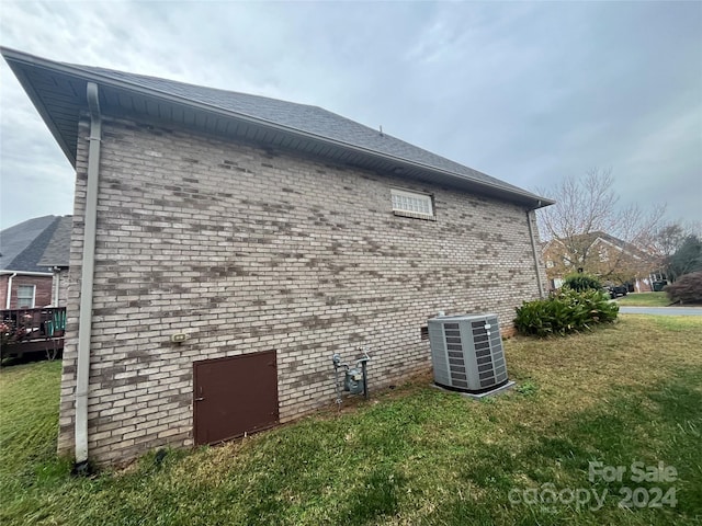 view of side of home featuring a yard and central AC