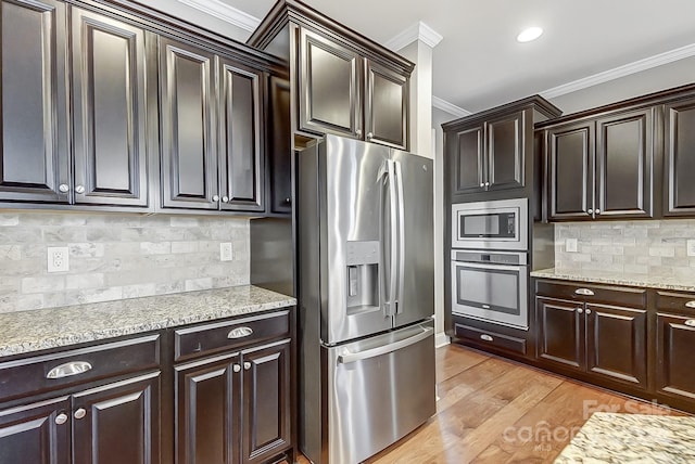 kitchen featuring tasteful backsplash, ornamental molding, appliances with stainless steel finishes, dark brown cabinets, and light hardwood / wood-style floors