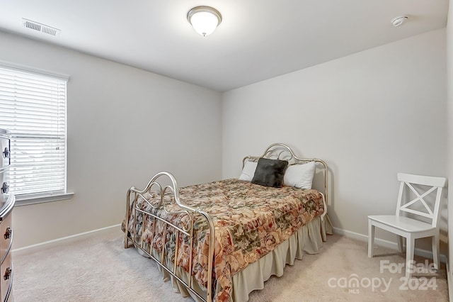 bedroom featuring light colored carpet and multiple windows