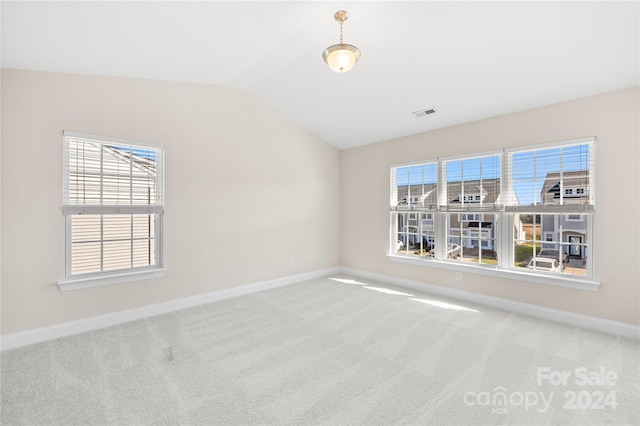 carpeted spare room featuring vaulted ceiling and a healthy amount of sunlight