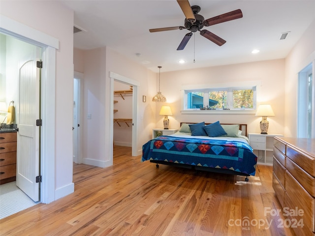 bedroom with a closet, light hardwood / wood-style flooring, a spacious closet, and ceiling fan