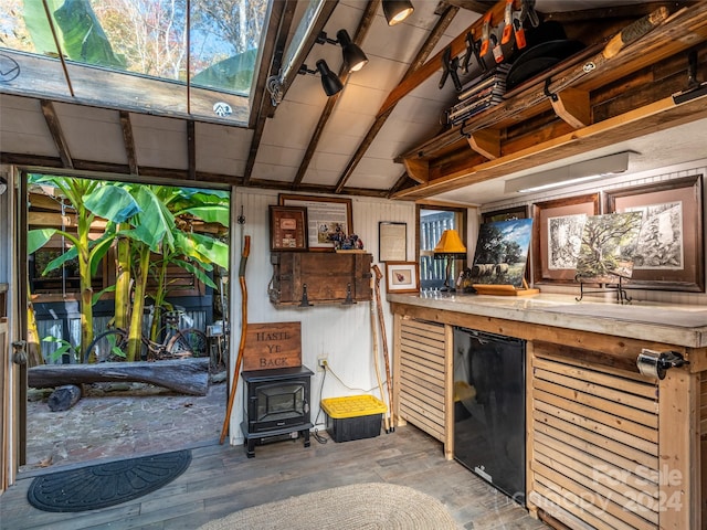 miscellaneous room with wooden walls, vaulted ceiling with beams, hardwood / wood-style flooring, and a wood stove