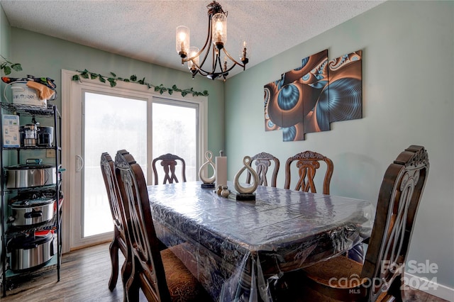 dining area with hardwood / wood-style floors, a textured ceiling, and a chandelier