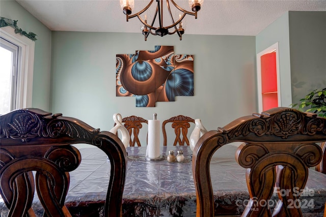 dining space with a textured ceiling and a notable chandelier