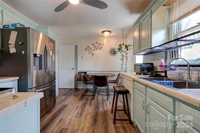 kitchen featuring backsplash, a textured ceiling, dark hardwood / wood-style flooring, stainless steel refrigerator with ice dispenser, and sink