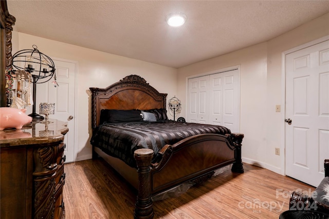 bedroom featuring light wood-type flooring, a textured ceiling, and a closet