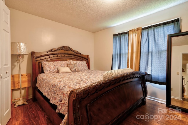 bedroom featuring a textured ceiling and dark hardwood / wood-style flooring