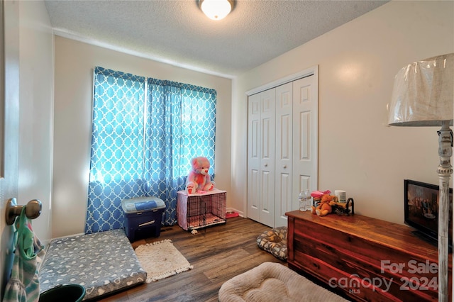 bedroom with hardwood / wood-style flooring, a textured ceiling, and a closet