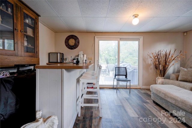 living room with dark hardwood / wood-style floors and a paneled ceiling