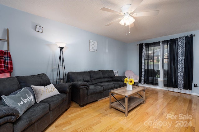 living room featuring ceiling fan, a textured ceiling, and light hardwood / wood-style flooring