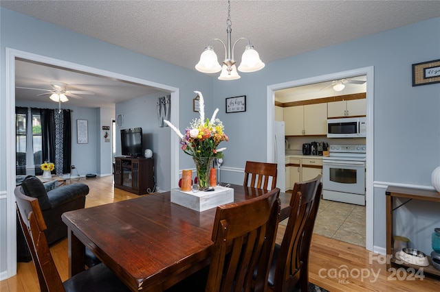 dining area with a textured ceiling, light hardwood / wood-style flooring, and ceiling fan with notable chandelier