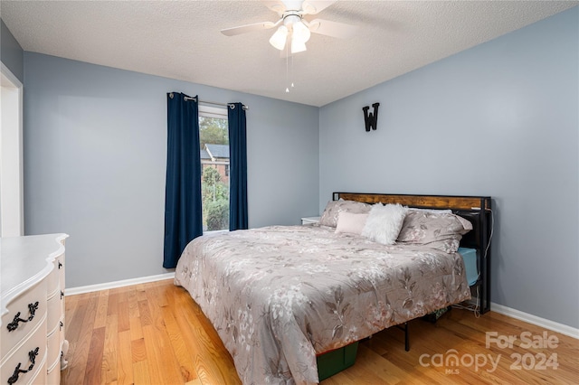 bedroom featuring light hardwood / wood-style floors, a textured ceiling, and ceiling fan