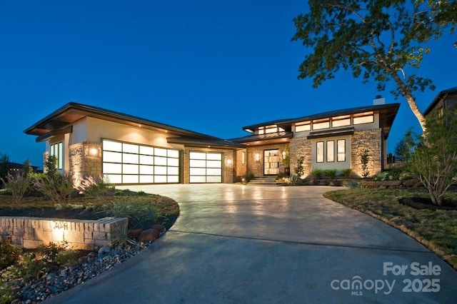 prairie-style house featuring stone siding, a garage, driveway, and stucco siding