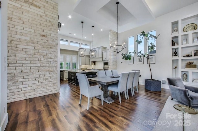 dining area featuring built in shelves, baseboards, a high ceiling, dark wood-style flooring, and a notable chandelier