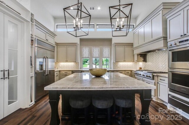 kitchen featuring visible vents, backsplash, a kitchen island, appliances with stainless steel finishes, and dark wood-style flooring