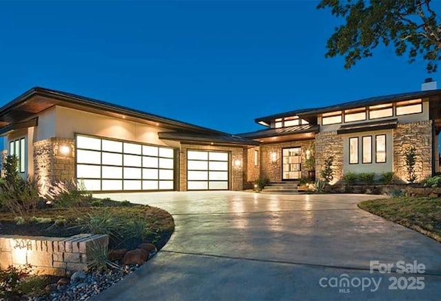 prairie-style house with an attached garage, stone siding, driveway, and stucco siding