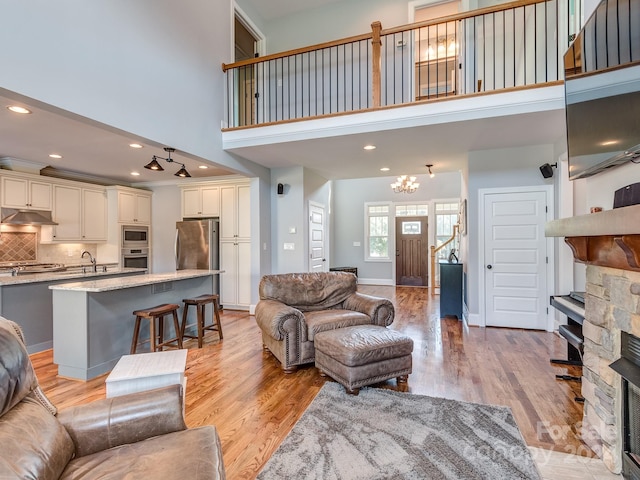 living room featuring sink, a high ceiling, a fireplace, and light hardwood / wood-style floors