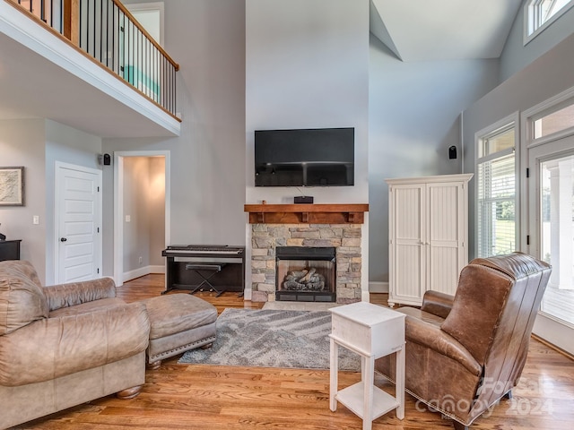 living room featuring a stone fireplace, hardwood / wood-style floors, and high vaulted ceiling