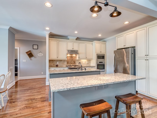 kitchen featuring light stone counters, stainless steel appliances, light wood-type flooring, and a kitchen island with sink