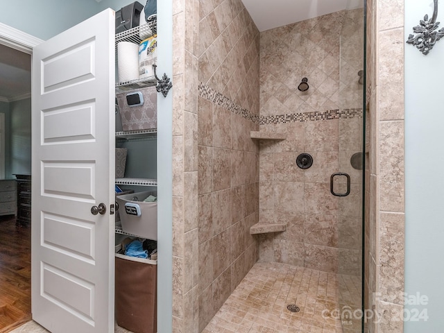 bathroom featuring crown molding, hardwood / wood-style flooring, and a shower with shower door