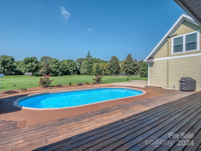 view of swimming pool featuring a wooden deck, a yard, and grilling area