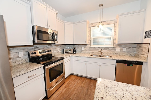 kitchen featuring appliances with stainless steel finishes, sink, decorative light fixtures, and white cabinets