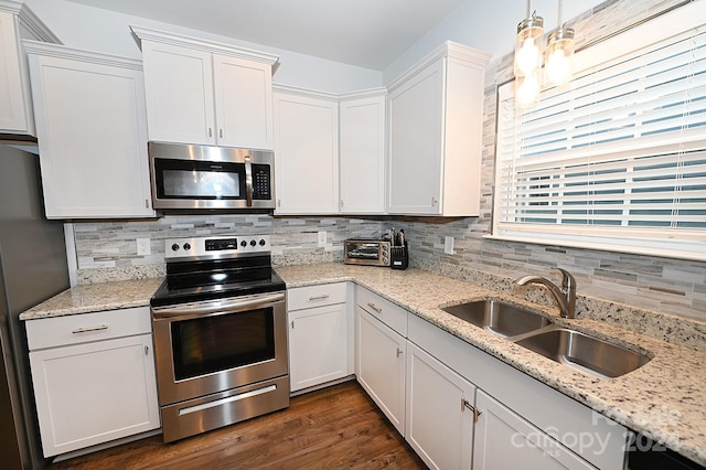 kitchen featuring dark wood-type flooring, hanging light fixtures, sink, white cabinetry, and appliances with stainless steel finishes