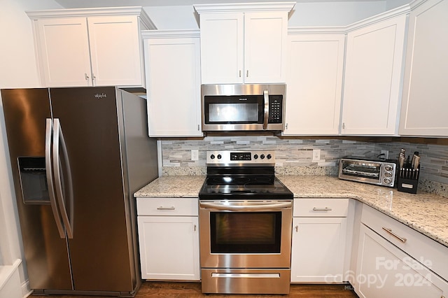 kitchen featuring white cabinets, tasteful backsplash, stainless steel appliances, and light stone counters