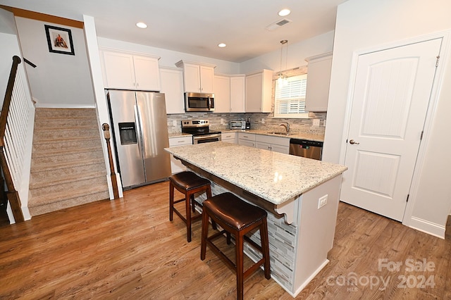 kitchen featuring light hardwood / wood-style floors, stainless steel appliances, pendant lighting, and a kitchen island