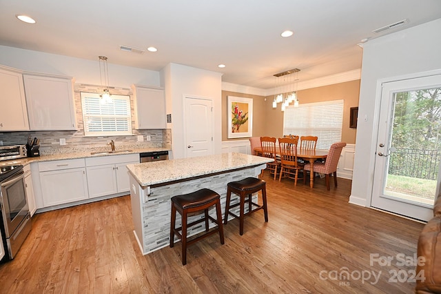 kitchen with light hardwood / wood-style flooring, a center island, white cabinetry, and decorative light fixtures