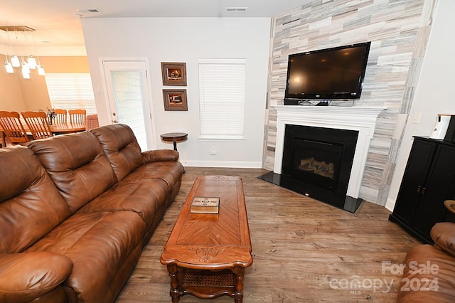 living room with an inviting chandelier, light hardwood / wood-style flooring, and a large fireplace