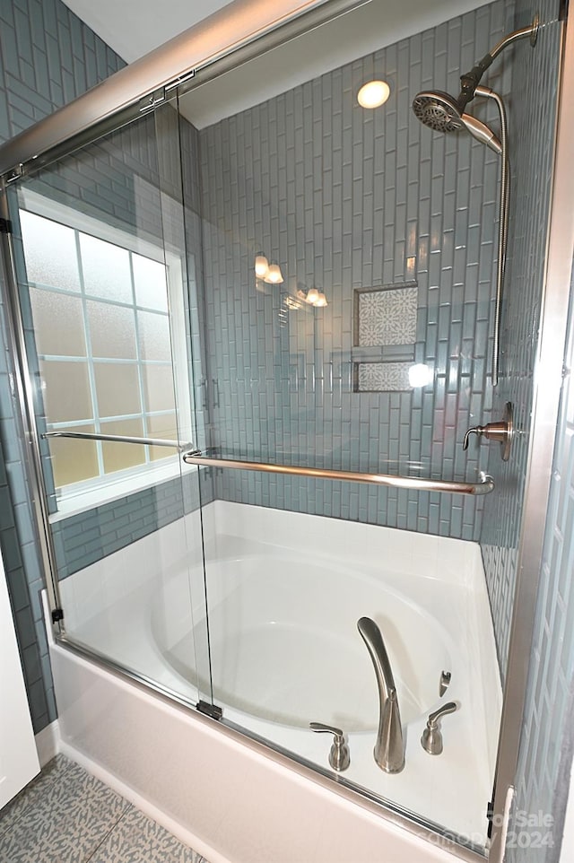 bathroom featuring tile patterned flooring and bath / shower combo with glass door