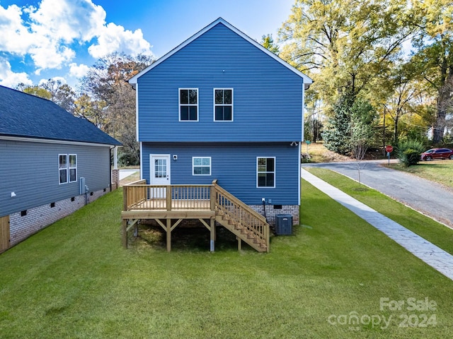 rear view of house featuring central air condition unit, a wooden deck, and a lawn