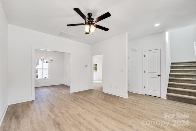 unfurnished living room featuring light hardwood / wood-style floors and ceiling fan with notable chandelier